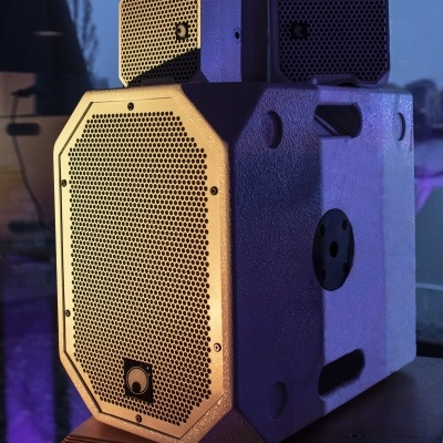 Coluna de som cinza claro com duas pequenas colunas empilhadas em cima em fundo de vidro reflexivo.