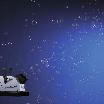 Máquina de bolhas de sabão branca em funcionamento, com bolhas contra fundo azul.