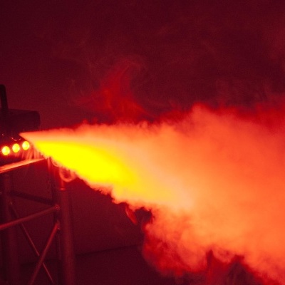 Equipamento de efeitos a emitir jato de nevoeiro alaranjado em ambiente escuro