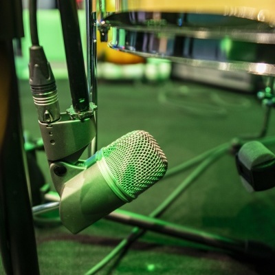 Microfone prateado perto de tambor transparente em piso verde