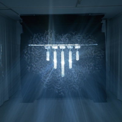 Candeeiro suspenso com cinco pendentes de vidro iluminados em ambiente escuro