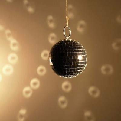 Bola de espelhos pequena pendurada refletindo luz na parede