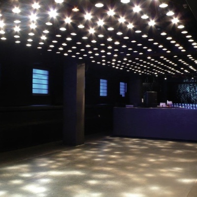 Espaço interior de discoteca com iluminação de lâmpadas no teto e balcão azul