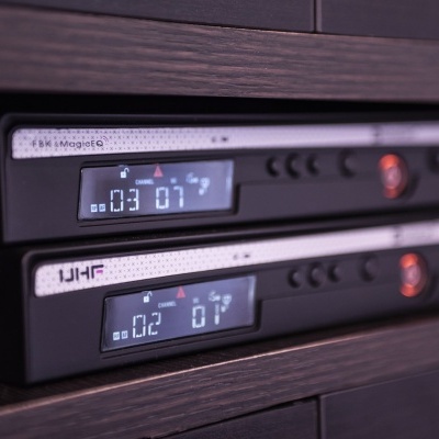 Rádio FM digital preto com display azul a mostrar 103.7 e botões de controle