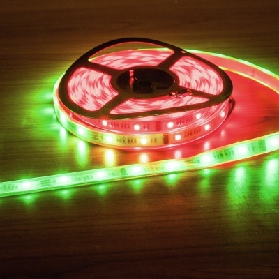 Rolo de fita LED bicolor vermelho e verde sobre superfície de madeira clara