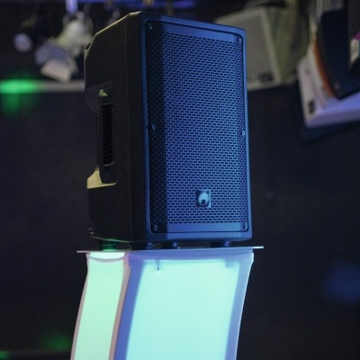 Coluna de som preta sobre pedestal branco iluminado