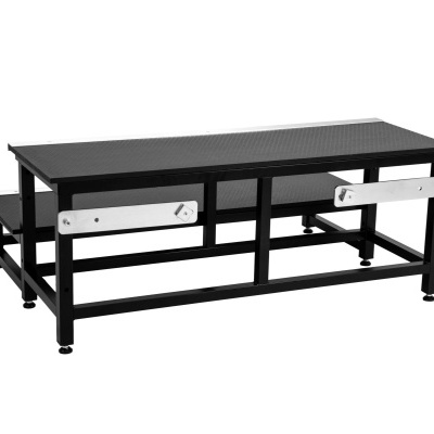 Estrutura metálica preta com duas plataformas retangulares texturizadas e placas prateadas laterais