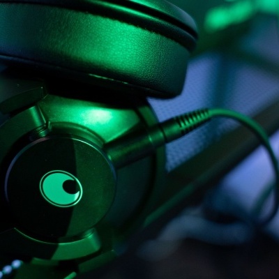 Auscultadores preto com detalhes verdes e logótipo circular abstrato