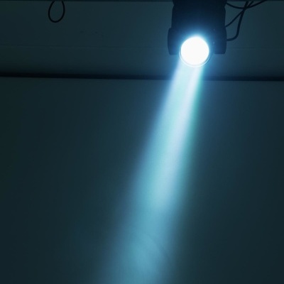 Foco de iluminação pendurado com feixe de luz branca numa parede cinzenta