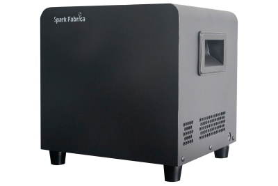 Caixa cúbica preta com a inscrição Spark Fabrica e ventilação lateral.