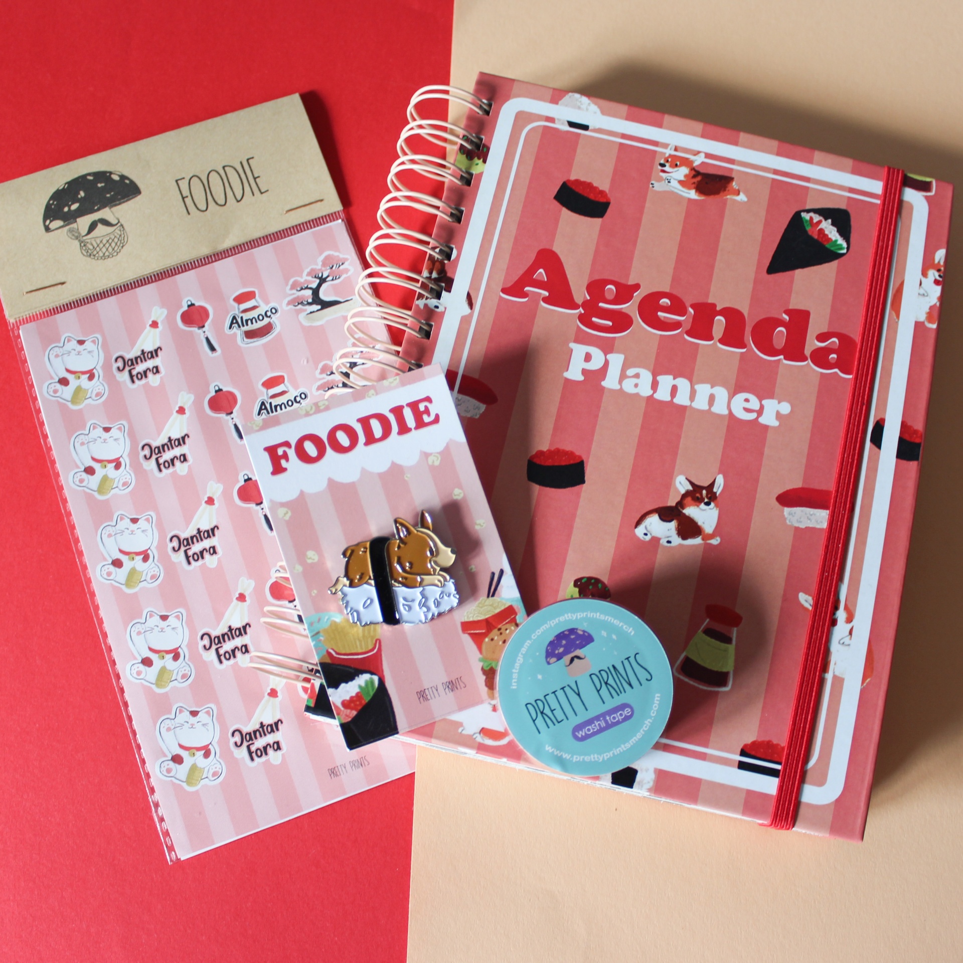 Agenda planner rosa com ilustrações de sushi e gatos, autocolantes temáticos, lápis com palavra FOODIE e carimbo PRETTY PRINTS