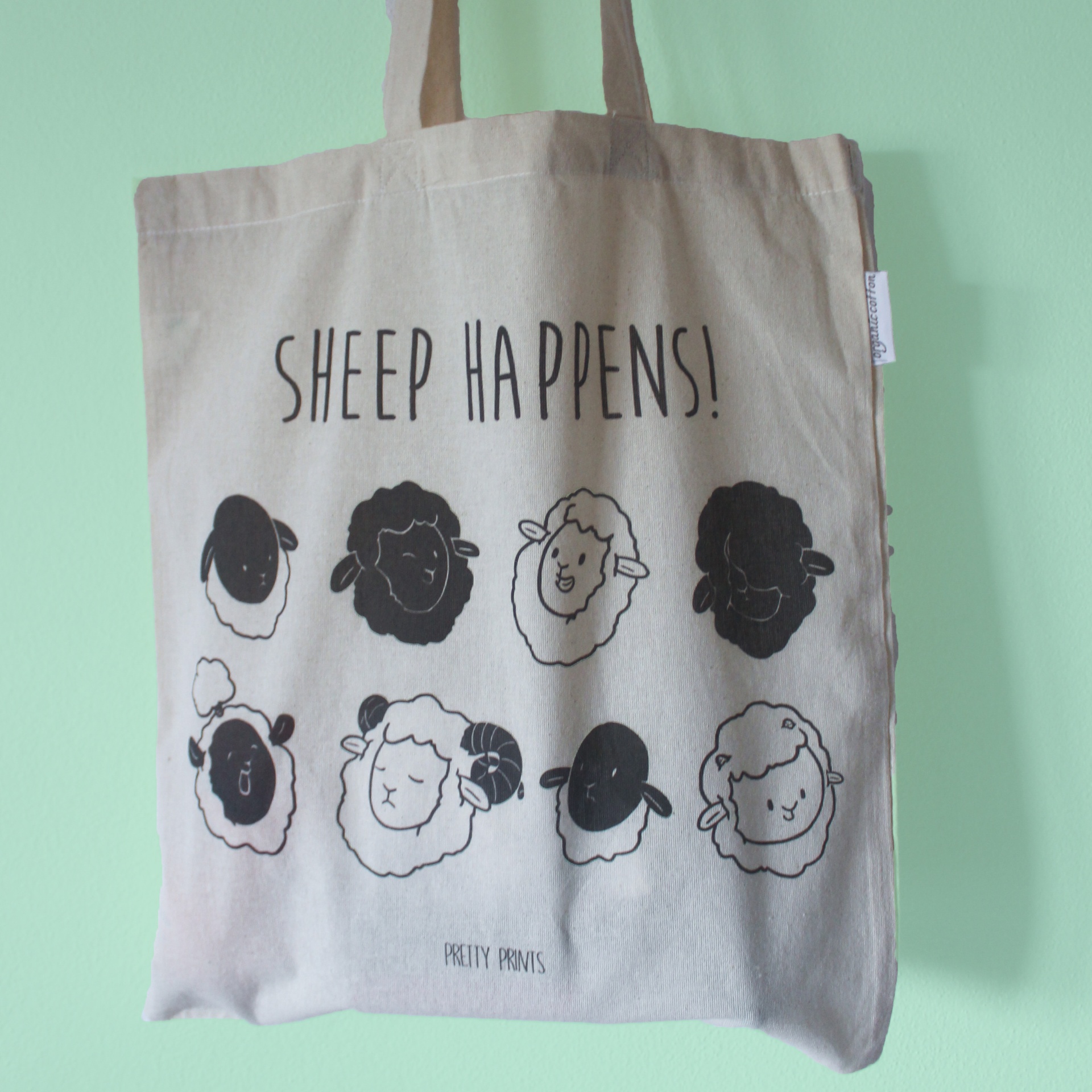 Saco de tecido bege com ilustrações de ovelhas e texto SHEEP HAPPENS