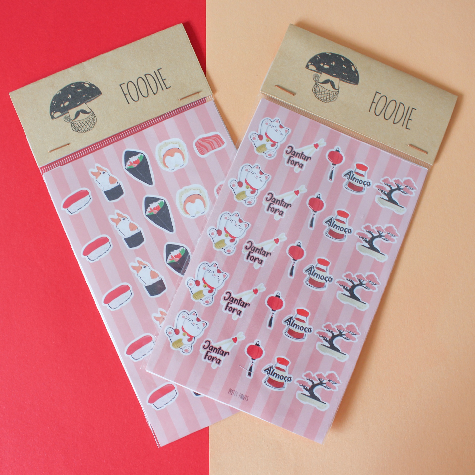 Dois pacotes de autocolantes FOODIE com desenhos de sushi e maneki-neko sobre riscas rosa