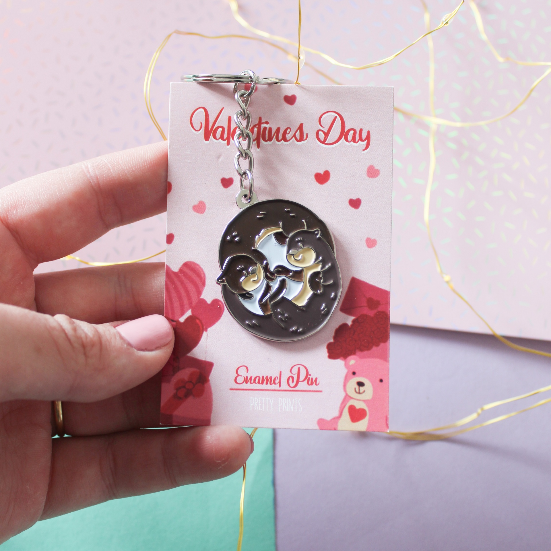 Chaveiro de gatos em metal prateado com fundo de cartão decorativo com corações vermelhos e texto Valentine's Day