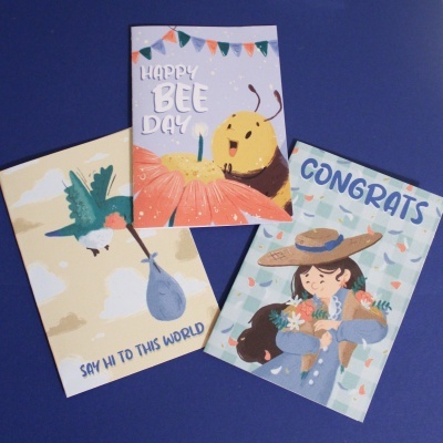Três cartões coloridos ilustrados com abelha, beija-flor e menina, com textos em inglês, sobre fundo azul.