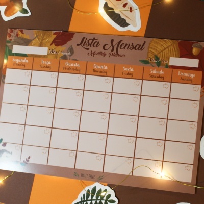 Plano mensal para organização com dias da semana em português e inglês em fundo decorado com folhas e luzes