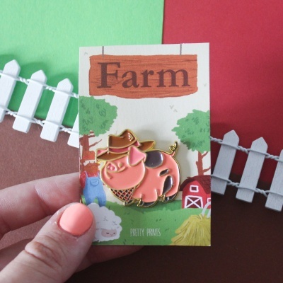 Pin metálico de porco rosa em cartão com texto FARM com mini cerca branca ao fundo