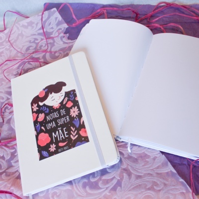 Dois cadernos brancos, um aberto e um fechado com capa ilustrada e texto em português