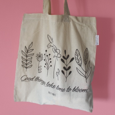 Saco de tecido bege com desenhos de plantas e texto preto