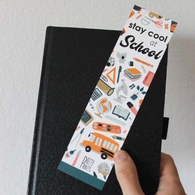 Marcador de livros colorido com texto stay cool at School sobre livro preto.