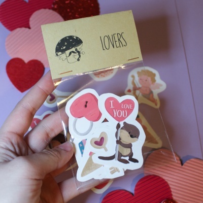 Pacote de autocolantes românticos embalado em saco transparente com etiqueta 'LOVERS' e fundo rosa com corações