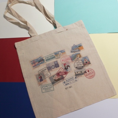 Saco de tecido bege com selos coloridos de locais portugueses e alças longas