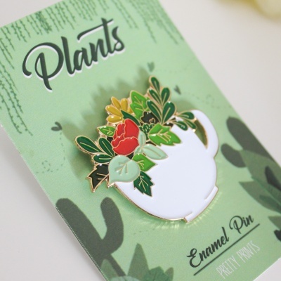Pins esmaltado de jarro branco com flores e folhas em cartão verde 'Plants'.