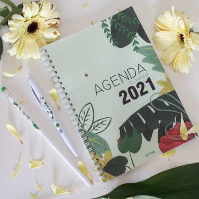 Agenda 2021 com capa decorada e canetas brancas com padrão verde em fundo branco com flores amarelas