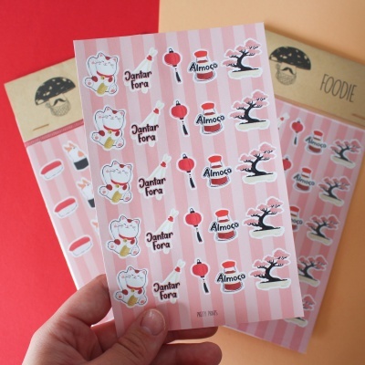 Folha de autocolantes com gatos da sorte e lanternas sobre fundo rosa listrado