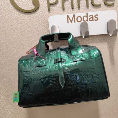 Mala de mão verde metálica com padrão embutido e etiqueta colorida pendurada