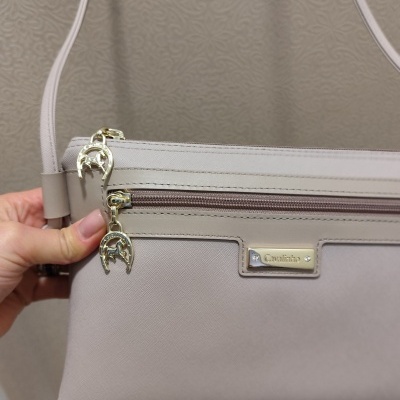 Mala de tiracolo beige clara com detalhes dourados e pendentes de ferradura