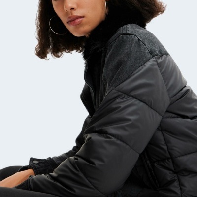 Mulher com casaco preto matelassado e gola de pêlo.