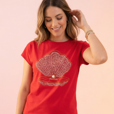 Mulher a usar t-shirt vermelha com estampa de concha em pedraria brilhante e pérola no centro.