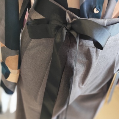 Calças cinzentas com cinto preto de fita e camisa geométrica colorida