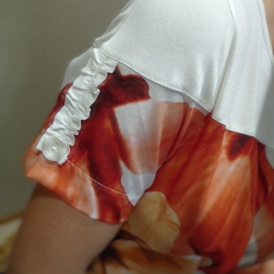 T-shirt feminina branca com detalhe franzido e padrão colorido em vermelhos e laranja