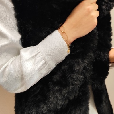 Casaco ou colete de pêlo sintético preto com camisa branca e pulseira dourada