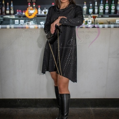 Mulher com vestido preto brilhante e botas pretas em bar