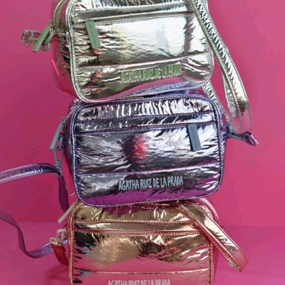Três malas pequenas metálicas em prateado, roxo e dourado com o nome AGATHA RUIZ DE LA PRADA