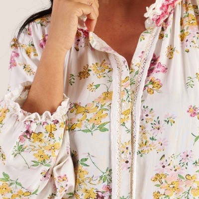 Blusa feminina branca com padrão floral amarelo e rosa e detalhes rendados