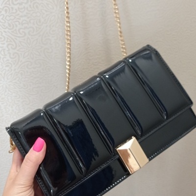 Mala de mão preta com fecho dourado e alça de corrente