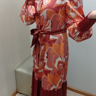 Vestido comprido floral em tons de laranja e castanho com cinto e mangas bufantes.