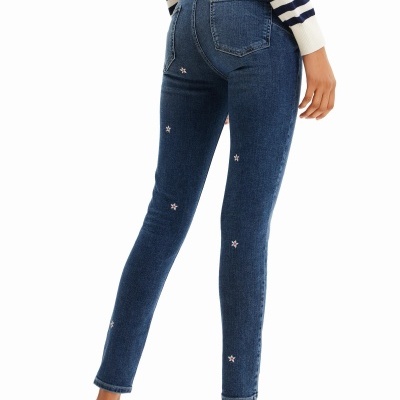 Calças de ganga azul com estrelas bordadas e ténis brancos