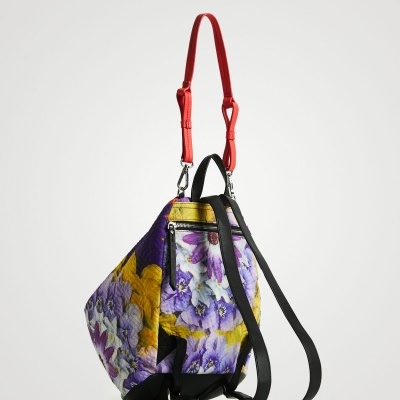 Mochila floral em tecido com alças pretas e vermelhas.