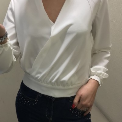 Blusa branca de manga comprida com decote em V e calças jeans escuras com pedraria