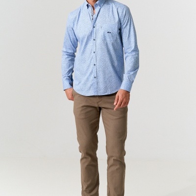 Homem com camisa azul clara de padrão pequeno e calças castanhas, sapatos azul escuro