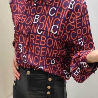 Camisa com padrão de letras coloridas e calças pretas de couro com botões dourados