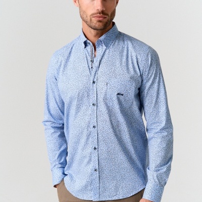 Homem a usar camisa azul clara com padrão de pequenos motivos escuros contra fundo branco