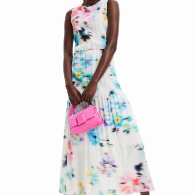 Mulher veste vestido tie-dye e segura mala cor-de-rosa
