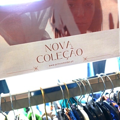 Cabide metálico com roupas penduradas e letreiro da nova coleção