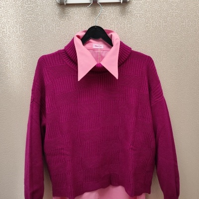 Camisola roxa de malha com camisa rosa clara penduradas em cabide preto